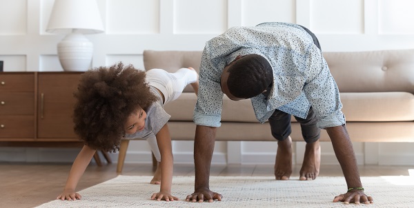 father and small daughter in casual clothes do pushup exercise on carpet on warm floor in living room 